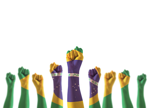 Imagem de mãos levantadas para cima e revestidas com a bandeira no Brasil